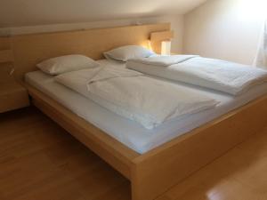 a large bed with white sheets and pillows at Ferienwohnung Allmein Top 3 in Vandans