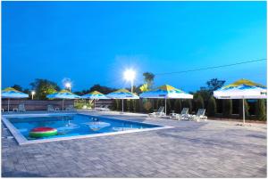 a swimming pool with blue umbrellas and chairs at La Relian in Partizanii