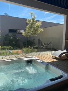 a hot tub in a backyard with a deck at Brit Hotel, Spa & Restaurant - Colmar Est in Bischwihr