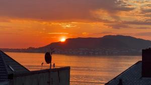 un coucher de soleil sur un plan d'eau avec le soleil couchant dans l'établissement Ålesund sentrum apartment, à Ålesund