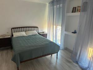 a bedroom with a bed with a green blanket and a window at Gandia Borjia in Gandía