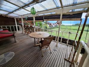 a patio with a table and chairs on a deck at 3 Bedroom Lake House in Bedugul