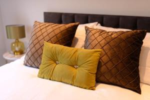 a bed with a yellow pillow and brown pillows at Stunning Liverpool City Location with River View and parking space included in Liverpool