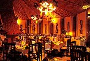 Amboseli Sopa Lodge في أمبوسيلي: غرفة طعام بها طاولات وكراسي وثريا