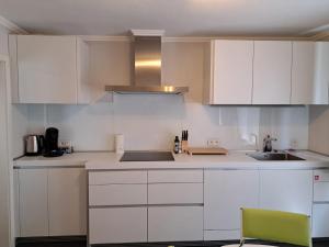 a white kitchen with white cabinets and a green chair at Vitus-Perle in Saint-Vith +20 photos