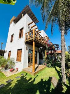 ein weißes Haus mit einer Veranda und einer Palme in der Unterkunft Casa Branca BG in Barra Grande