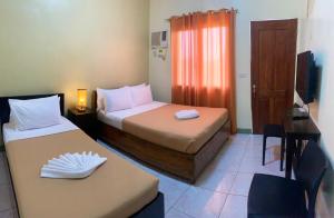 a room with two beds and a desk and a television at Coron Vista Lodge in Coron