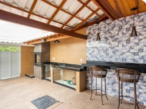 a kitchen with a counter and two bar stools at Triplex Belíssimo in Cabo Frio +8 photos