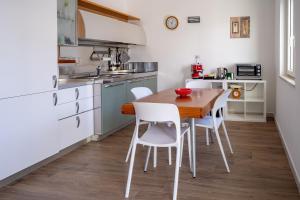 a kitchen with a wooden table and white chairs at Le Stagioni di Heraclea in Policoro