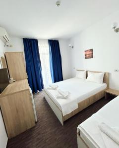 a hotel room with two beds and blue curtains at RIMA Del Mar in Eforie Nord