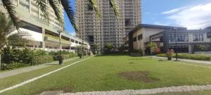 a large lawn in front of a building with tall buildings at Comfy 2 Bedroom Condominium at Verdon Parc Ecoland in Davao City