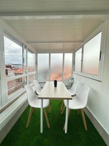 a table and chairs in a room with windows at Ático en el Centro de Cambados in Cambados +14 photos