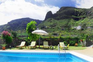 einen Pool mit Stühlen, einem Sonnenschirm und einem Berg in der Unterkunft Holiday Home El Mar in San Juan de la Rambla