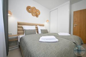 a bedroom with two beds with white towels on them at Dąbki Beachfront Retreat in Dąbki