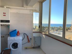 een wasruimte met een wasmachine en ramen bij Perla marina in Casa Santa