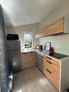 a kitchen with a stainless steel refrigerator and wooden cabinets at Mobilhome Bahia - 4 ou 6 voyageurs - Terrasse in Bidart