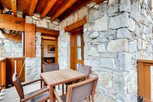 a dining room with a stone wall and a wooden table and chairs at Résidence Les Arcs 1950 Le Village - maeva Home - Appartement 2 pièces 4 personnes - Prestige MAE-2911 in Arc 1950
