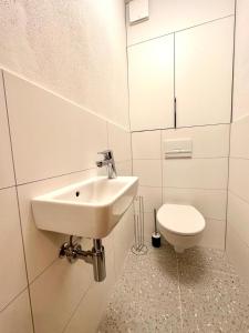 a white bathroom with a sink and a toilet at City appartment AC & Parking in Prievoz