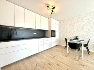 a kitchen with white cabinets and a table and a sink at City appartment AC & Parking in Prievoz +3 photos