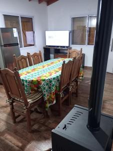 een eetkamer met een tafel, stoelen en een televisie bij EL RANCHO DE PIA in Merlo