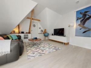 ein Wohnzimmer mit Sofa und Fernseher in der Unterkunft Backstage Apartment Kiel-Holtenau in Kiel