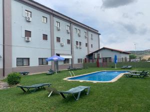 a building with a swimming pool in the grass next to a building at Hotel Ciudad de Plasencia in Plasencia