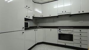 a white kitchen with white cabinets and a sink at O Xardín Termal in Ourense