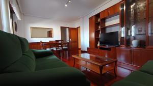 a living room with a green couch and a tv at O Xardín Termal in Ourense