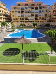 a swimming pool with an umbrella in front of a building at Casa Marius in La Mata