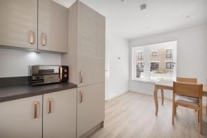 a kitchen with white cabinets and a table with a microwave at Dunmore Rooftop in Glasgow