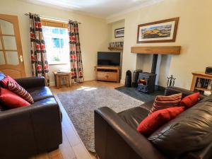 un soggiorno con un divano in pelle e una televisione di Bleaberry Cottage a Penrith
