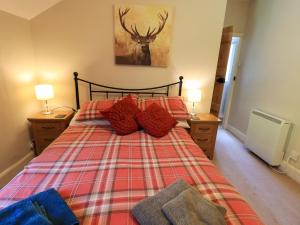 una camera da letto con un letto con cuscini rossi e un dipinto di un cervo di Bleaberry Cottage a Penrith