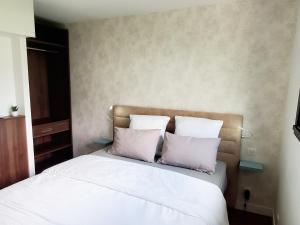 a bedroom with a bed with white sheets and pillows at Au calme du Golf - Appartement Chic 5 étoiles in Hossegor