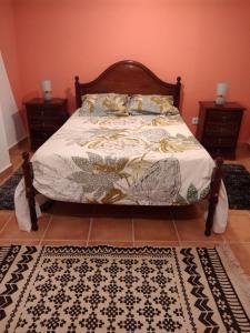 ein Bett in einem Schlafzimmer mit zwei Nachttischen und einem Teppich in der Unterkunft Casa Gama in Ribeira da Janela