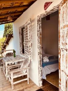 a room with a bed and a table and a window at Pousada Jardim da Praça in Caraíva