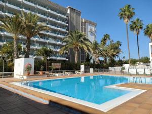 a swimming pool with palm trees in front of a building at Beach House in San Bartolomé de Tirajana