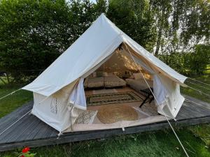a white tent with a bed in the grass at Rubeni in Stāķi