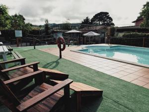 a swimming pool with two benches next to a swimming pool at Hotel Vitorio in Cudillero