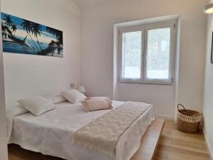 a white bedroom with a bed and a window at Holiday House in Villa Beatrice in Porto Istana +15 photos