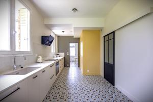 a kitchen with white cabinets and a tiled floor at Gîte de la Futaie-Maison de caractère au calme in Yvré-lʼÉvêque