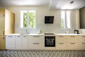 a kitchen with white cabinets and a sink and two windows at Gîte de la Futaie-Maison de caractère au calme in Yvré-lʼÉvêque +20 photos