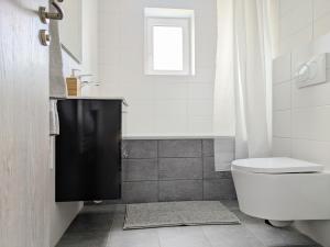 a white bathroom with a toilet and a window at Apartman Amanda - Ohrada in Choťánky