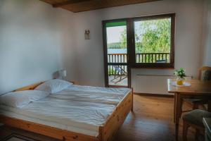 a bedroom with a bed and a window and a table at Agroturystyka nad jeziorem-Herrmann hof in Dejguny