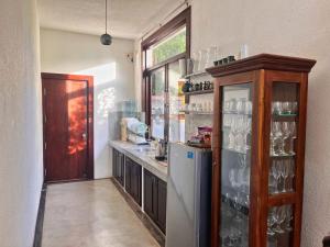 a kitchen with a refrigerator and a shelf with glasses at Nilaveli Bay Villa by Ceylon Spaces in Nilaveli