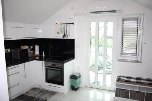 a kitchen with white cabinets and a black stove at Appartman Tia in Polje