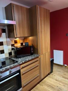 a kitchen with wooden cabinets and a microwave at MacIver City Apartments Farraline Court in Inverness +24 photos