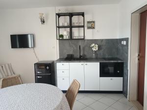 a kitchen with white cabinets and a sink and a table at Apartmani More Komarna in Komarna
