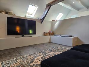 Una sala de estar con un televisor de pantalla plana grande. en La Jeannoterie, en Lithaire