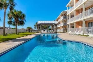 una piscina frente a un edificio con palmeras en Dauphin Island Beach Club 106B, en Dauphin Island