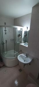 a bathroom with a tub shower and a sink at Apartment Mia in Sarajevo